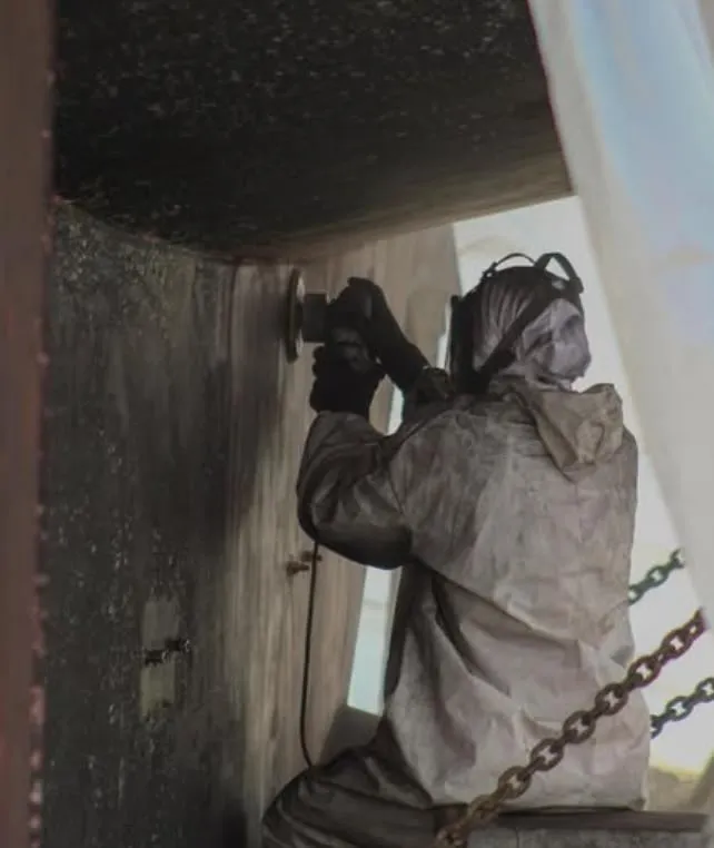 Technician sanding a hull in full protective gear